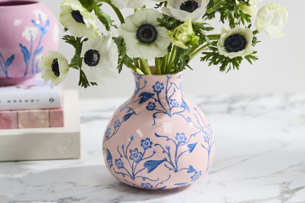 shown with white anemones and books on a table