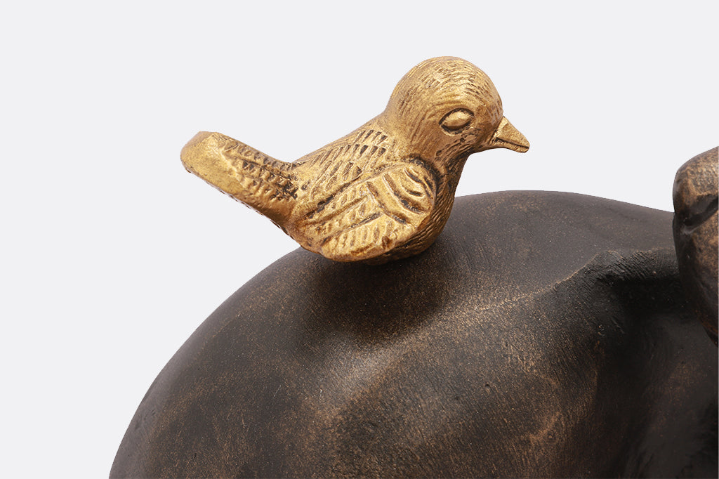 cast metal garden sculpture of dog looking at a bird on its back, close up of gold finish on bird