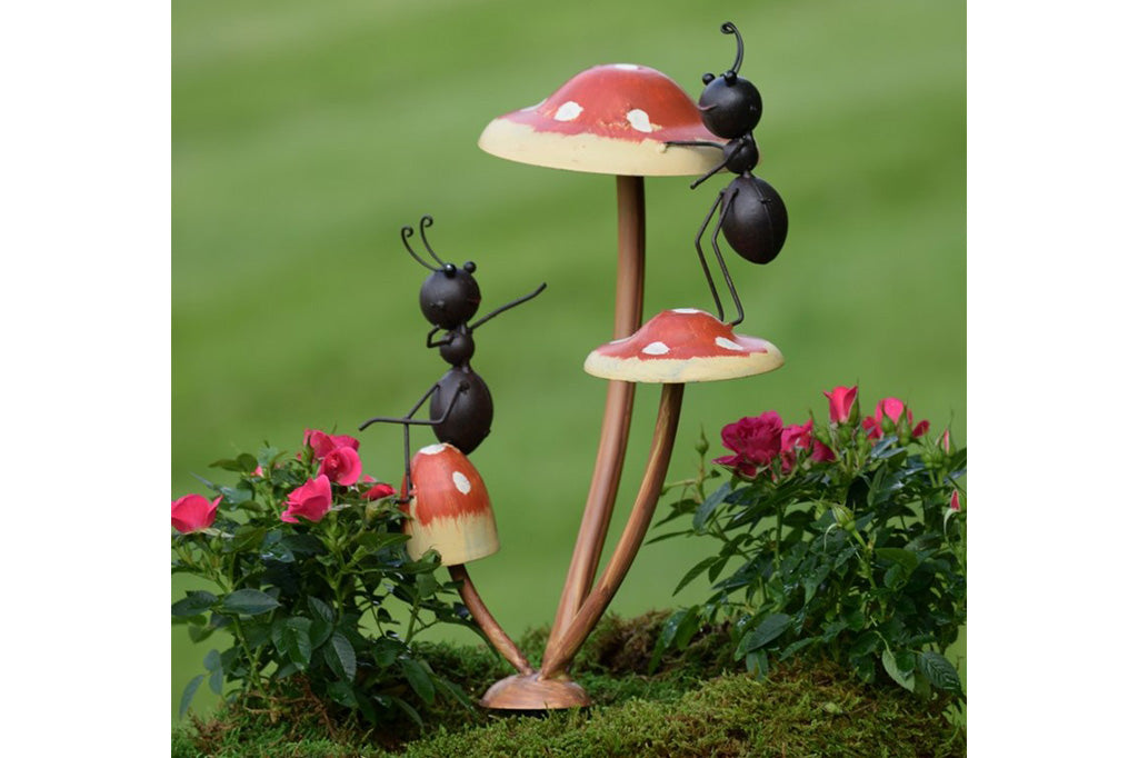 Metal garden accent of two ants frolic on a trio of mushrooms.