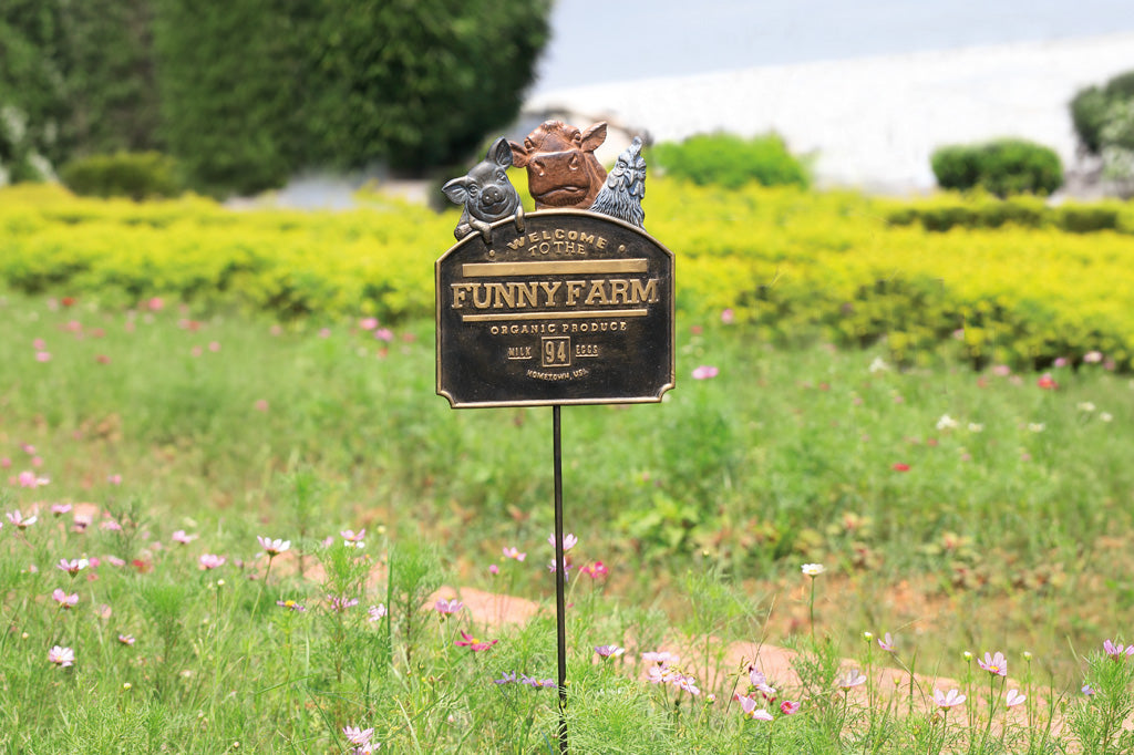Garden sign for 'Funny Farm' in a field with flowers and greenery