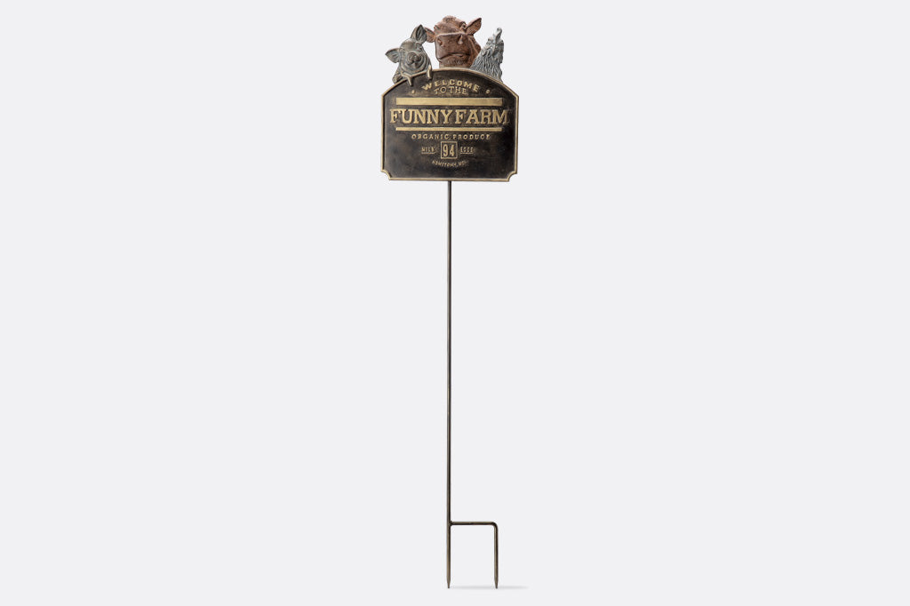 Metal sign on a stand with 'Funny Farm' text against a white background