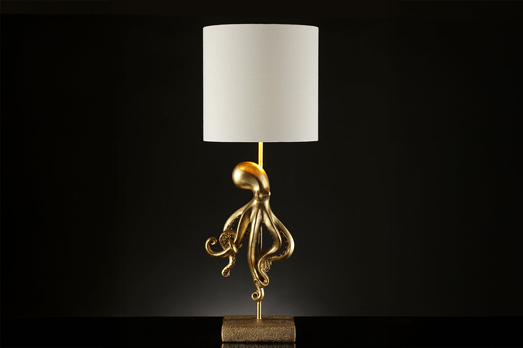 golden octopus lamp with white shade on dark background