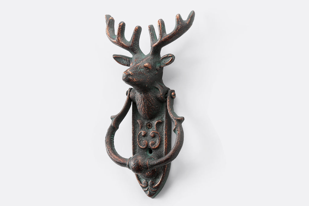 cast metal deer head with antlers and a horseshoe shaped knocker on rounded rectangle metal plate doorknocker face left