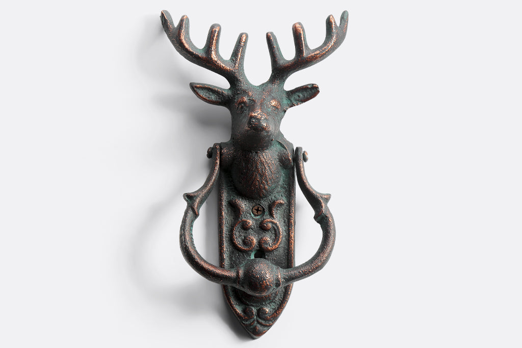 cast metal deer head with antlers and a horseshoe shaped knocker on rounded rectangle metal plate doorknocker