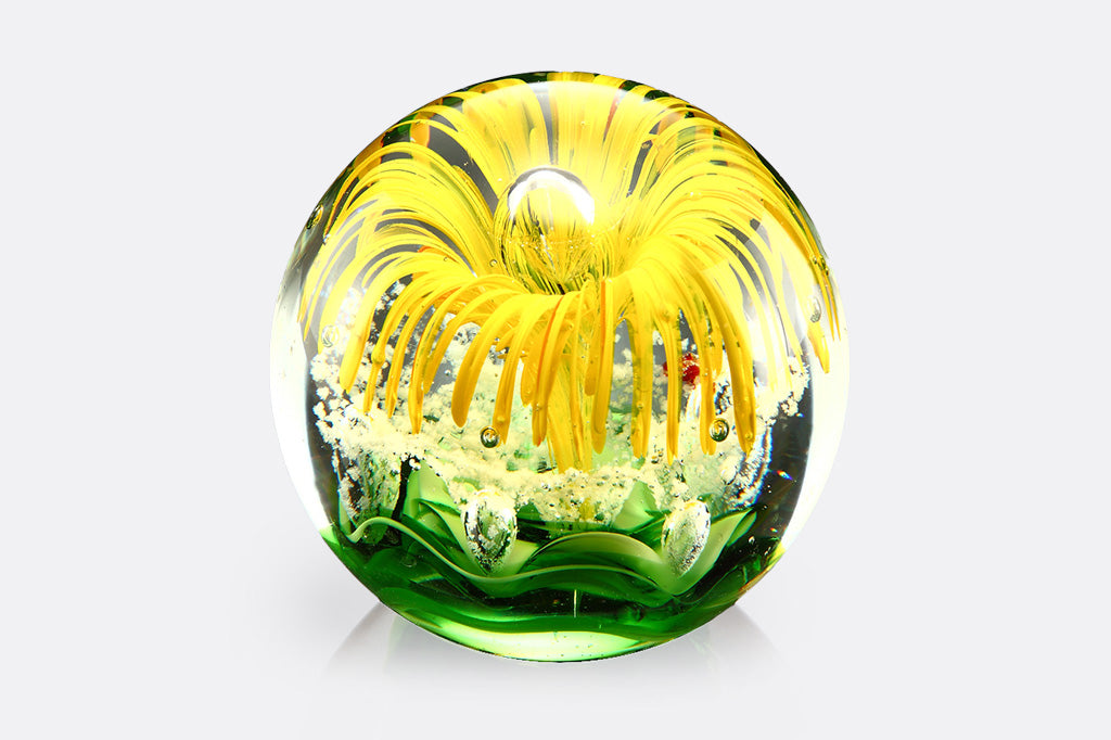 glass paperweight with yellow blossom and green leaf motif