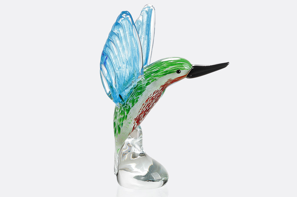 Glass hummingbird figurine with blue wings and green body on a white background
