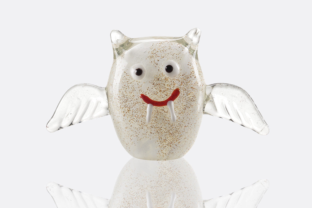 Glass figurine of a white and gold glitter bat with a smiling expression on a white background
