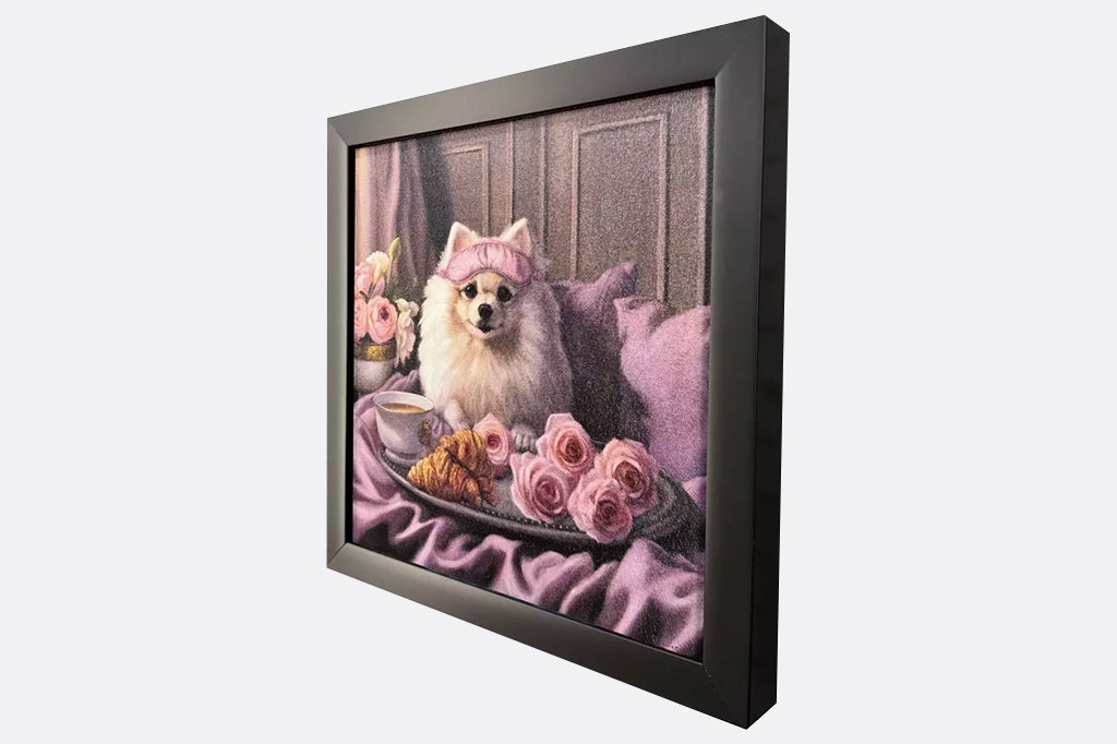 Framed artwork of a dog wearing a pink sleeping mask with a coffee cup, croissant, and flowers on a bed.