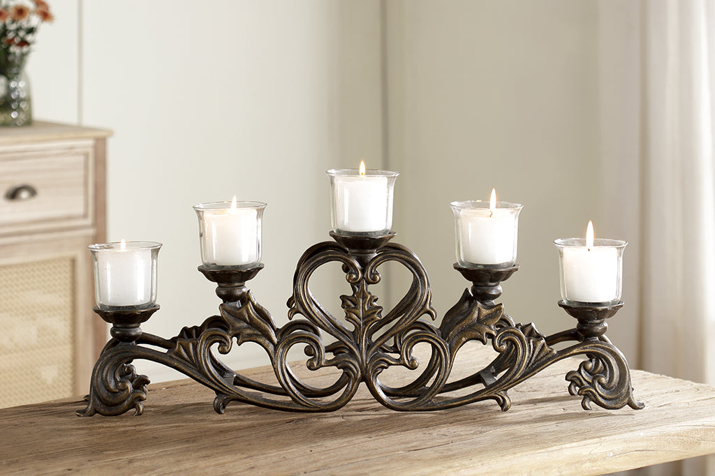 Candelabra with scrollwork and heart motif shown with 5 lit candles while on a wood table in dining room
