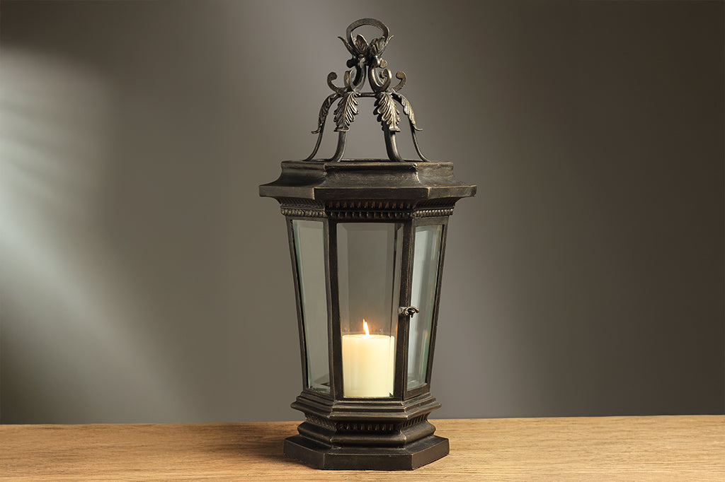 Decorative lantern with a candle on a wooden surface against a gray background