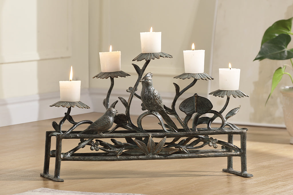 Fireplace suitable base decorative candle holder shown with 5 blossom stands amidst birds, butterfly, and plant stems