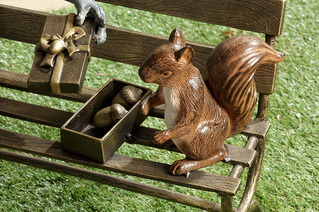 close up detail of squirrel on bench statue with a giftbox of acorns