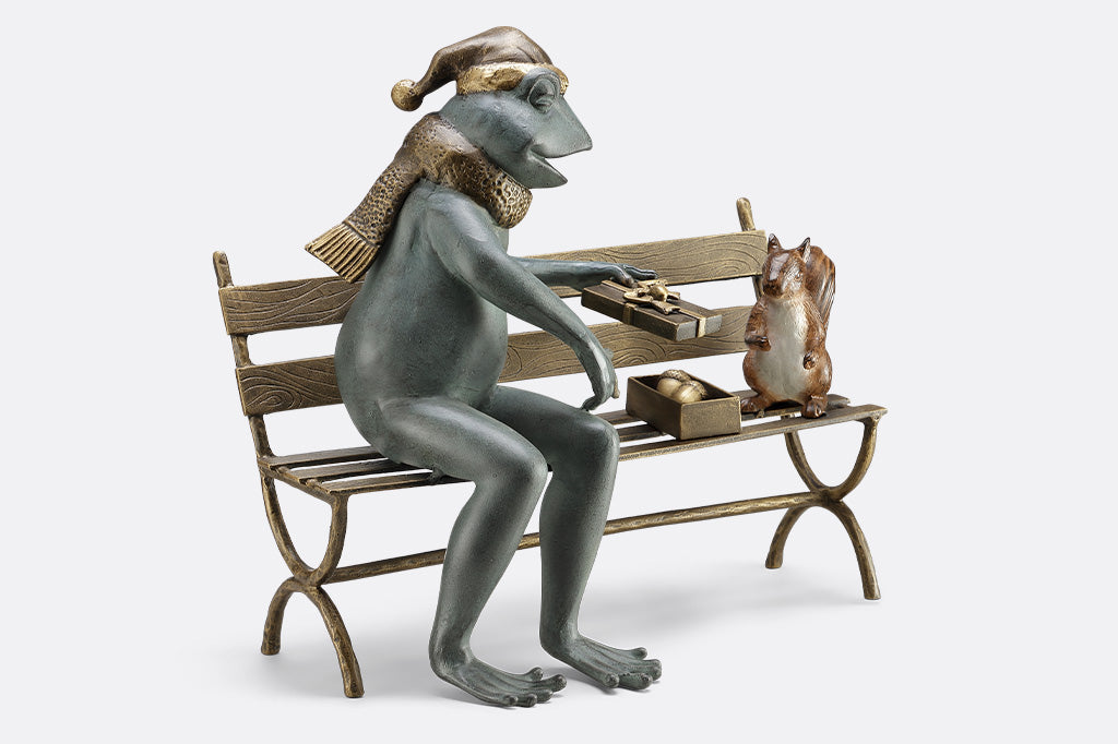 Frog and squirrel statue gifting an acorn on a bench