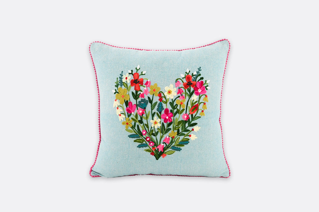 Decorative pillow with floral heart design on a light blue background
