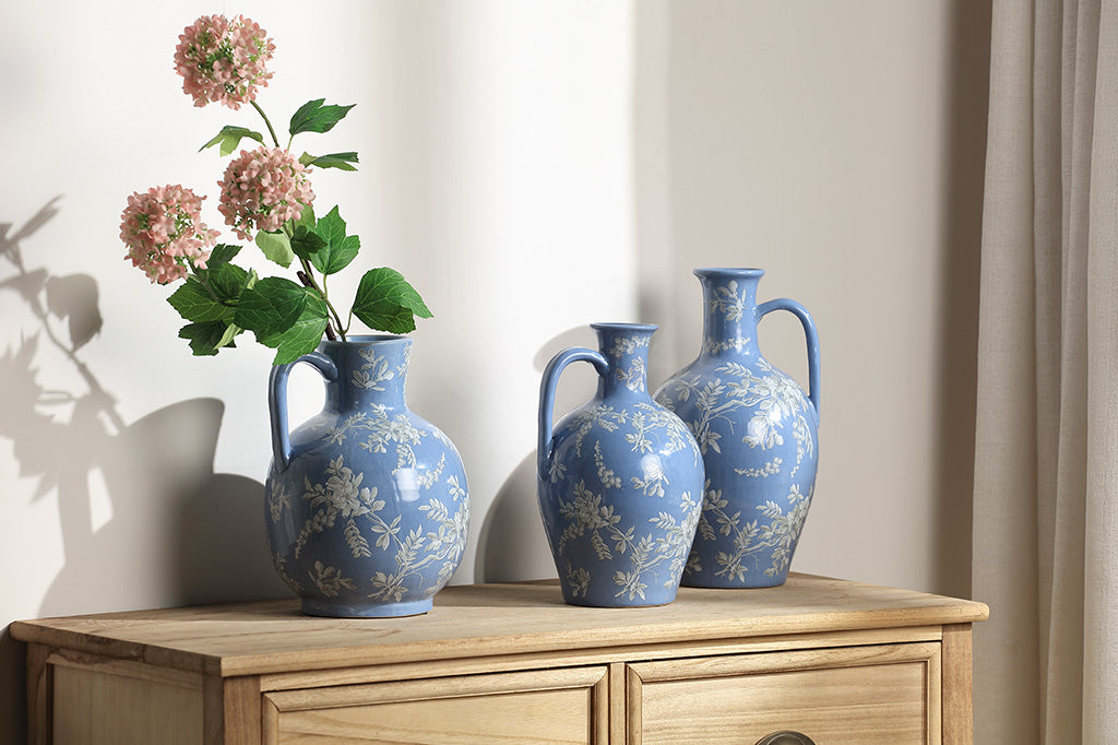 A short blue ceramic vase with white cornflower designs.