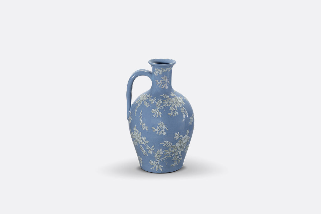 A short blue ceramic vase with white cornflower designs.