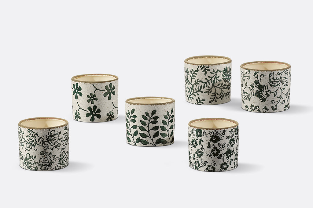 Set of six small ceramic pots with floral patterns on a white background