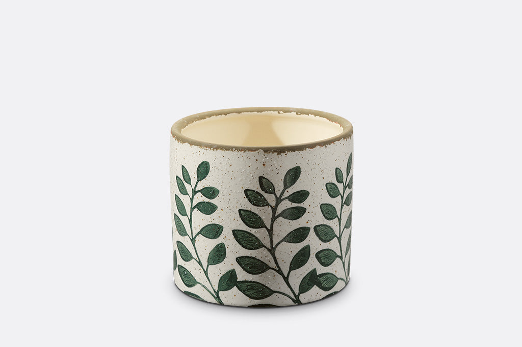 Ceramic planter with green leaf pattern on a white background