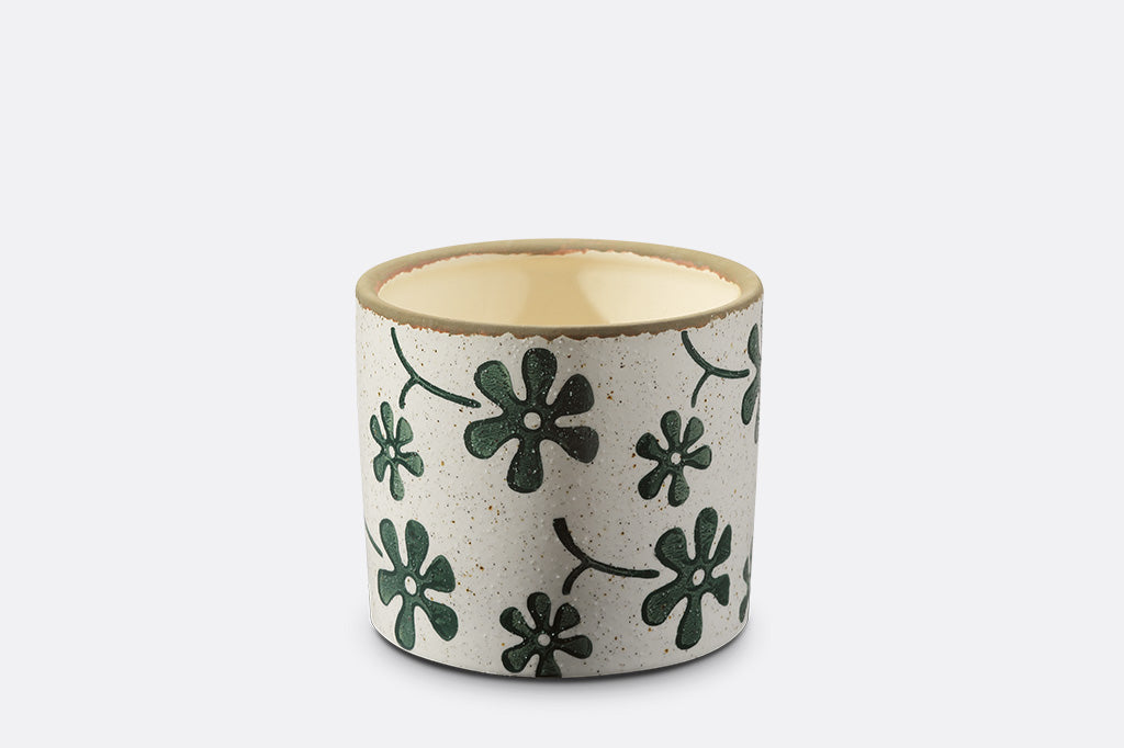 Ceramic planter with green floral patterns on a white background