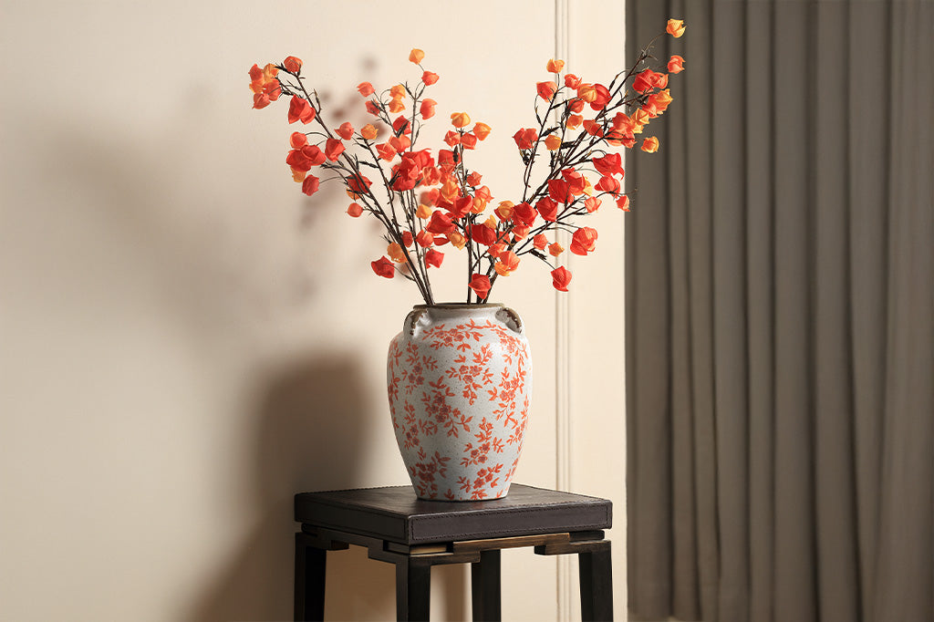 A vase jar with orange leaves and flowers.