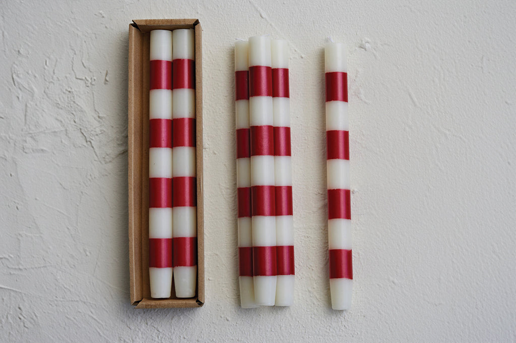 Stack of candy cane striped tapers on table; they come in packaged in a cardboard box - set of 4 in 2 boxes