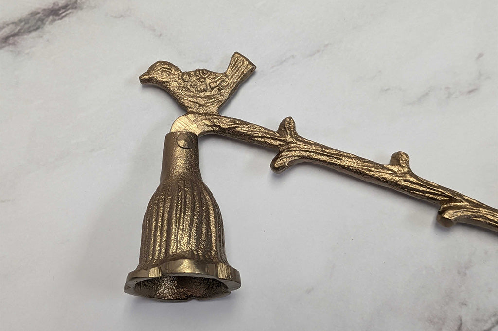 close up view of antiqued bronze candle snuffer with bird and branch motif
