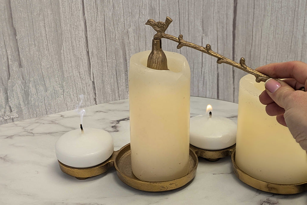 antiqued bronze candle snuffer with bird and branch motif being used to put out candles on table display