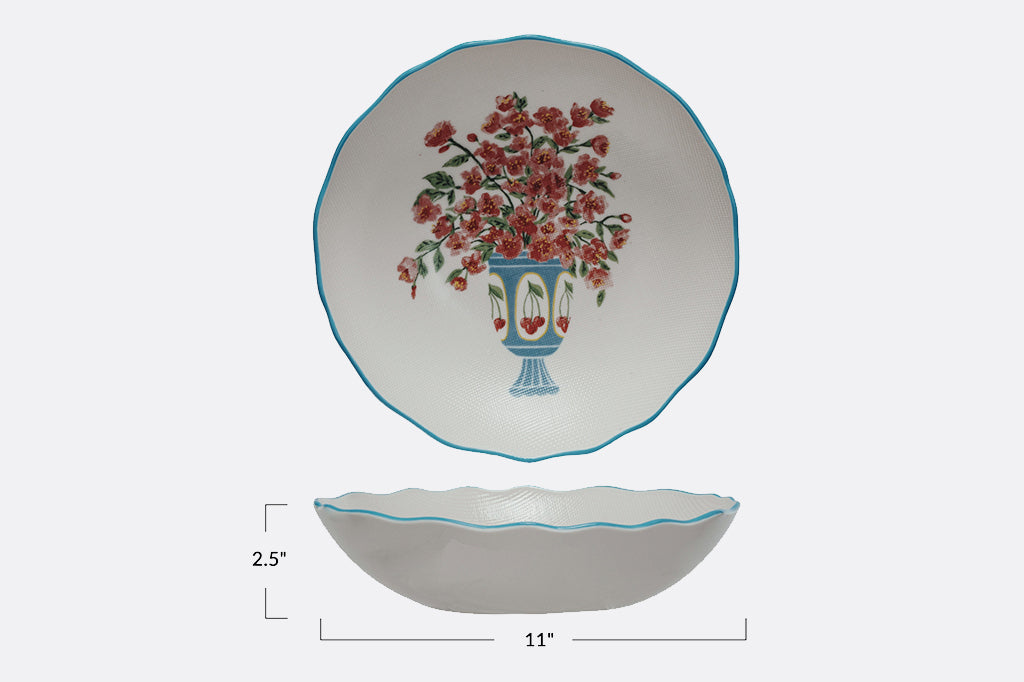 Stoneware bowl with scalloped edges painted in blue with floral arrangement in cheery vase