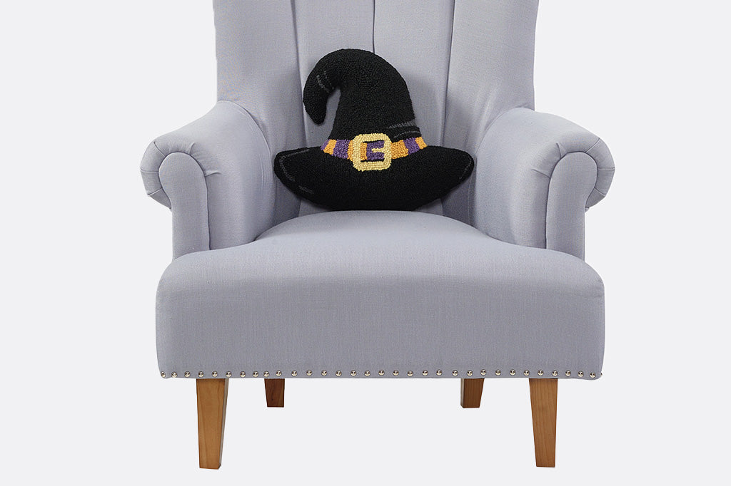 Black witch hat throw pillow on gray armchair