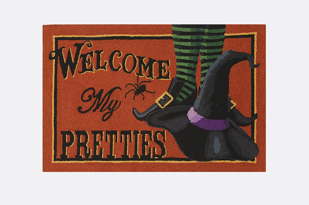 Halloween-themed doormat with witch's feet and text 'Welcome My Pretties' on an orange background.