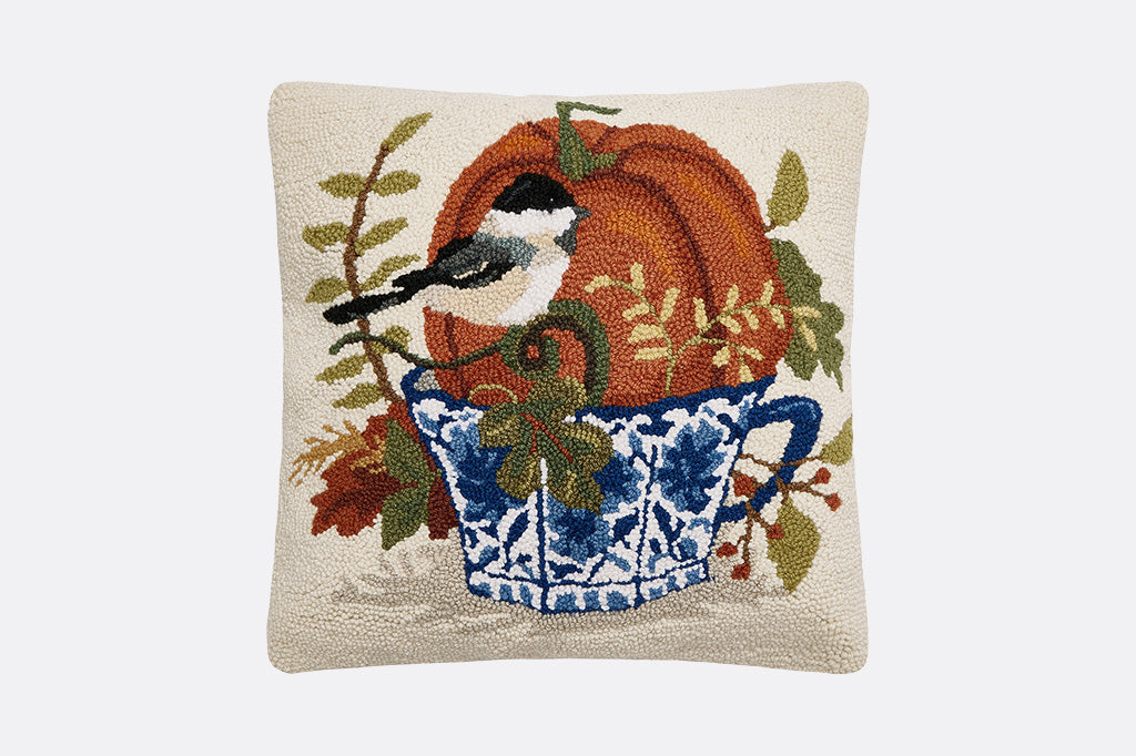Decorative pillow with a chickadee, pumpkin, and teacup design on a beige background