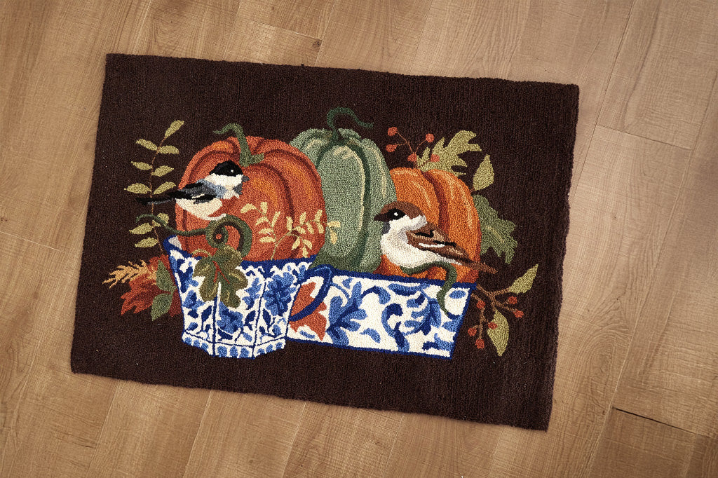 Decorative rug with pumpkins, birds, and a chinoiserie style basket motif set upon a wooden floor