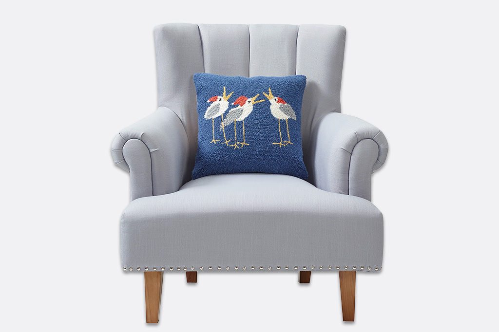 Gray armchair with a blue pillow featuring bird designs on a white background