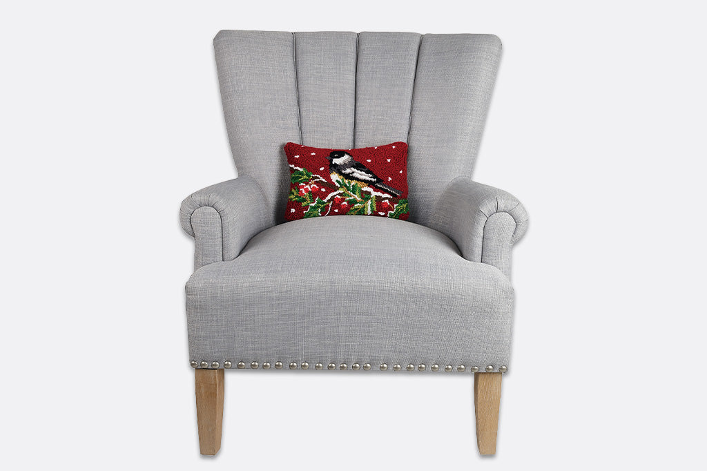 Gray armchair with a decorative pillow featuring a bird and berries on a white background
