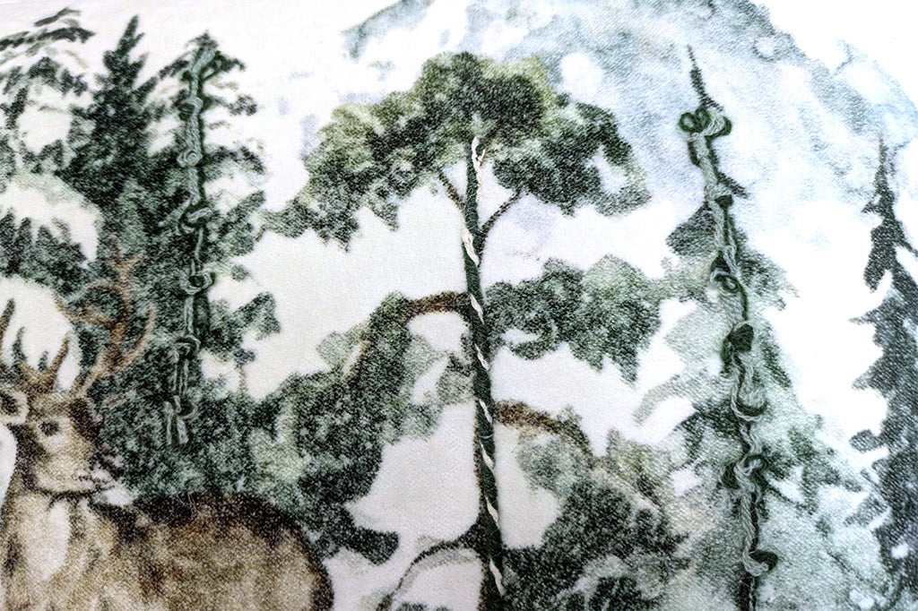 Illustration of a deer in a forest with trees and snow and spot embroidery on a velvety pillow