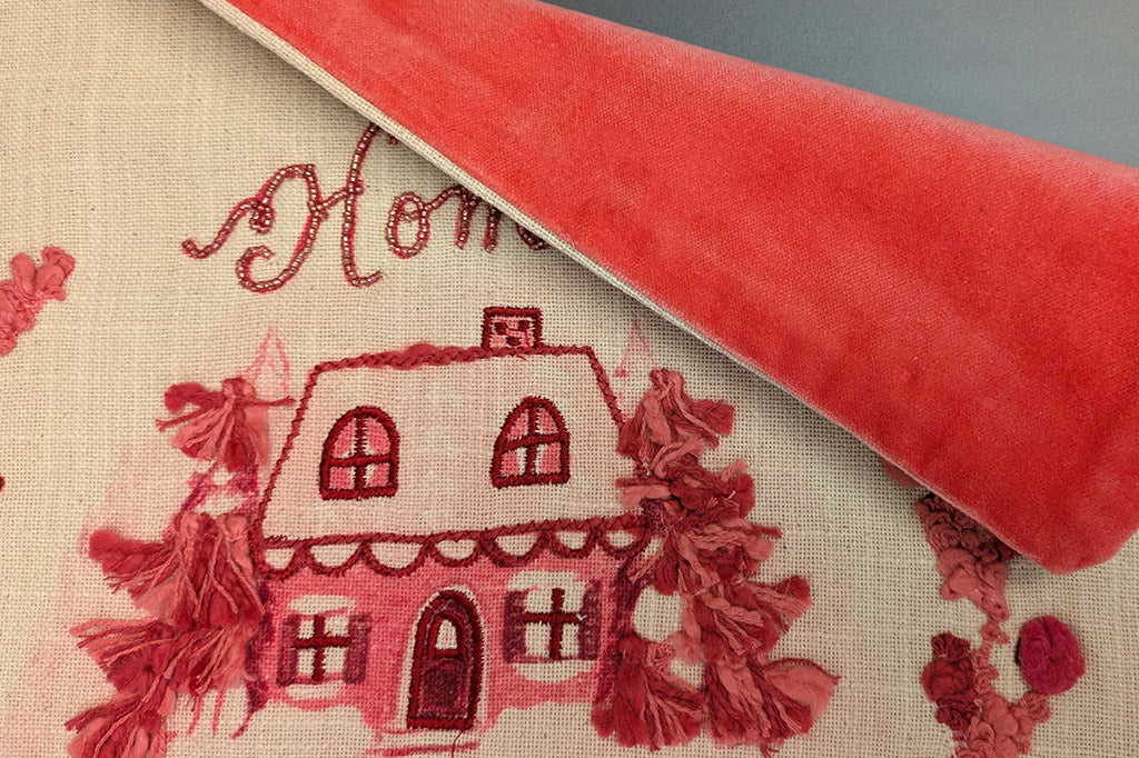 Embroidered house design on fabric with coral velvet backing