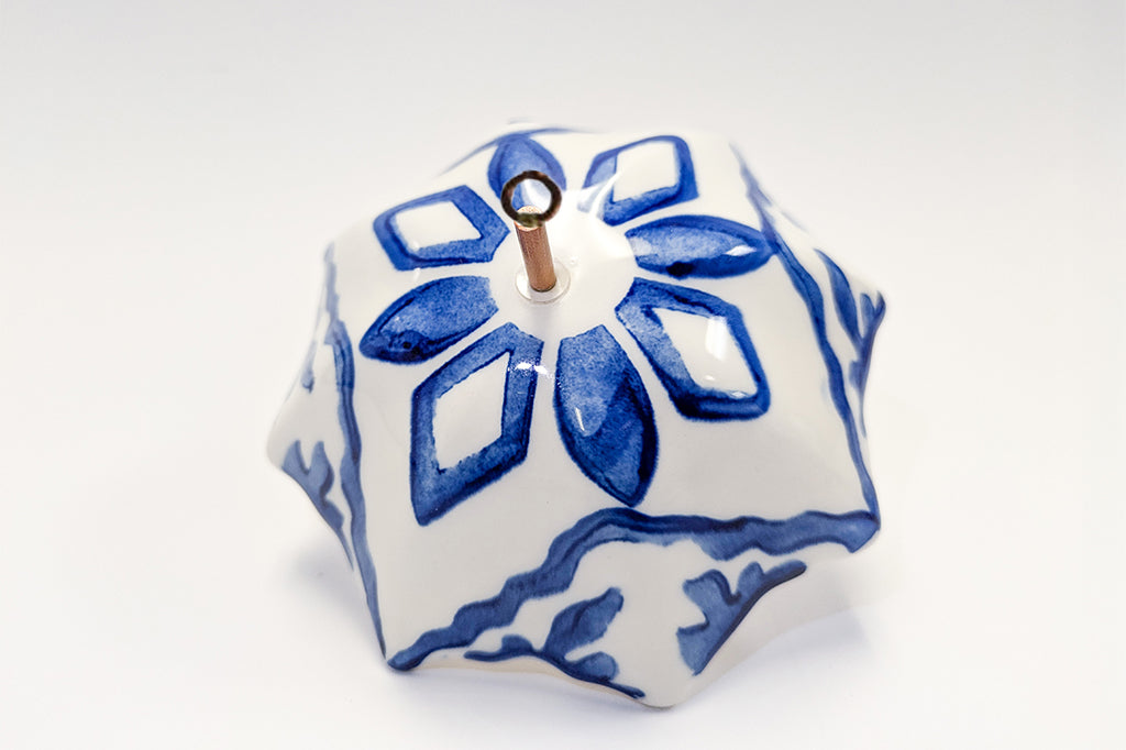 Decorative ceramic umbrella ornament with blue patterns on a white