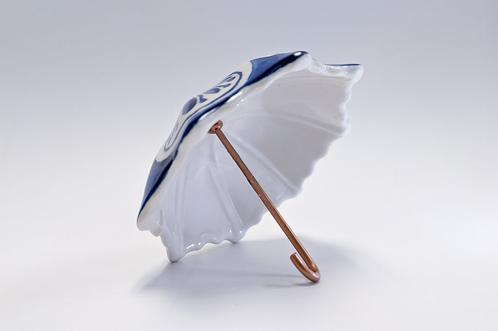 White ceramic umbrella with blue design on a light gray background