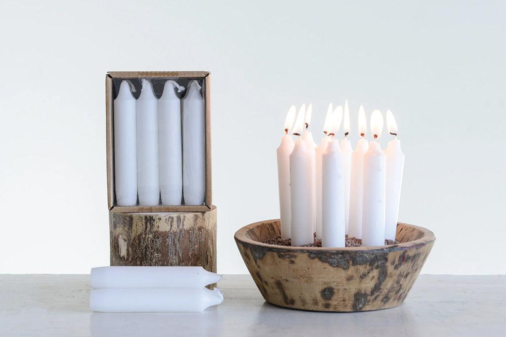 Set of 12 chubby stout white taper candles. Height of candles measures 5 inches. Set of 12 lit candles placed in wooden display bowl