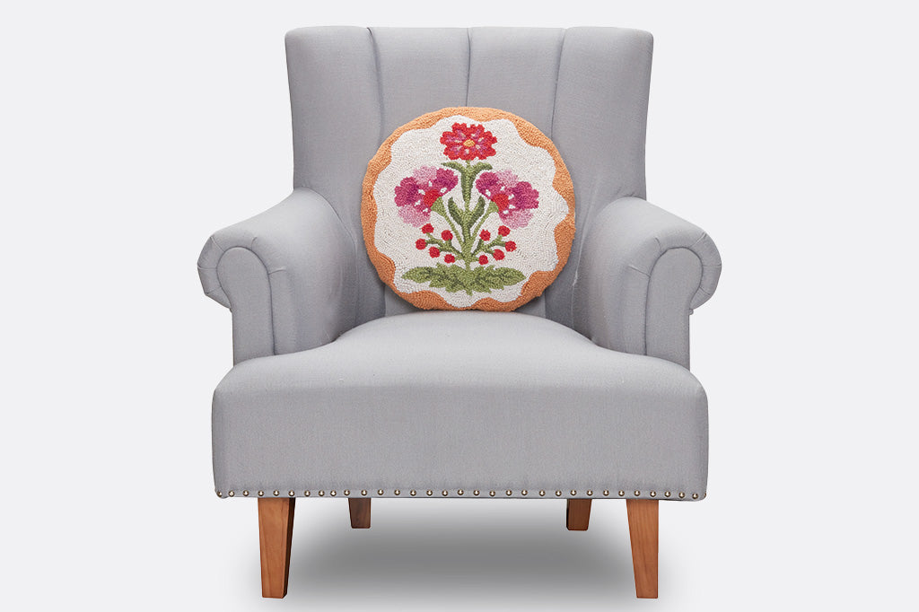 A circle hooked pillow with floral designs on a chair