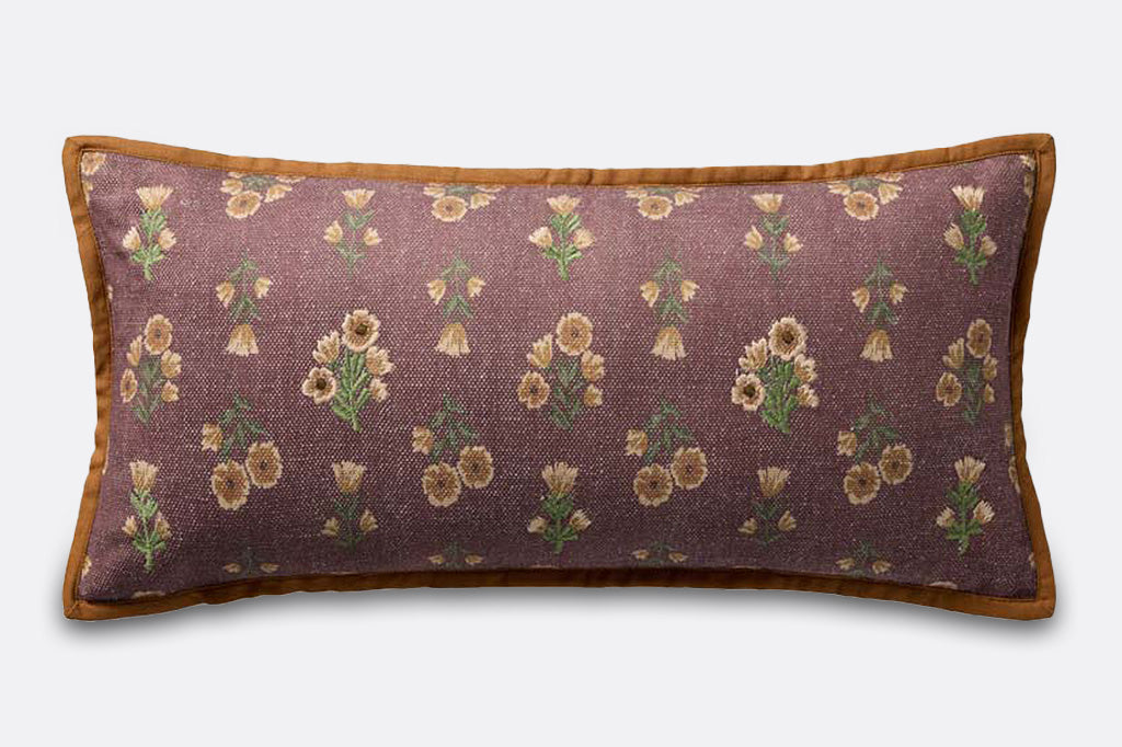 A dark reddish brown pillow with yellow and green flower patterns.