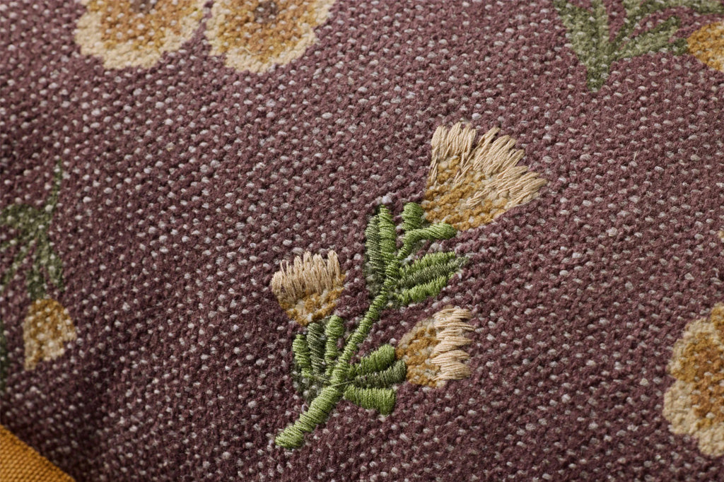 A dark reddish brown pillow with yellow and green flower patterns.