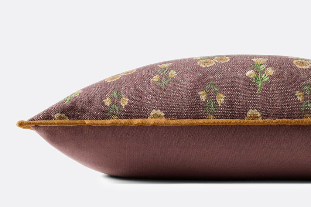 A dark reddish brown pillow with yellow and green flower patterns.