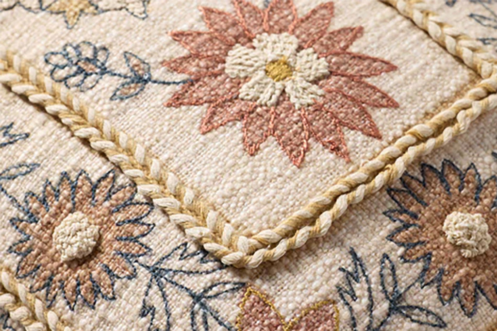 Close-up of a textured fabric with floral patterns and braided edges.