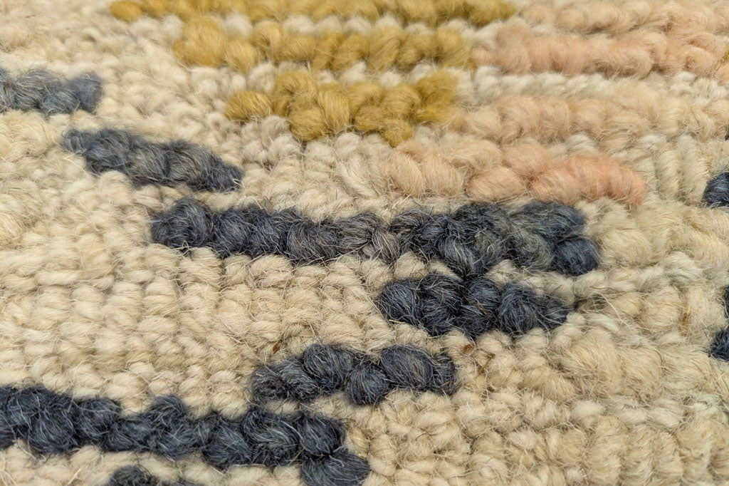 Close-up of a textured rug with multicolored yarn. Highly textured, there are woven striations of rich color.