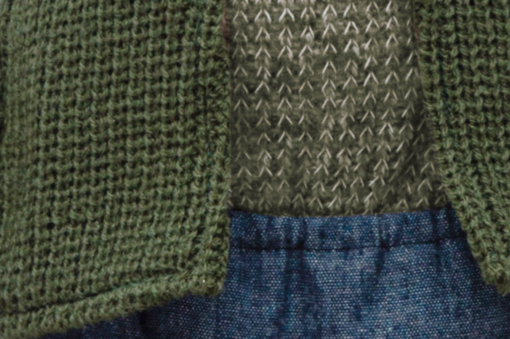 Frog stuffed animal wearing a green sweater and jean shorts.