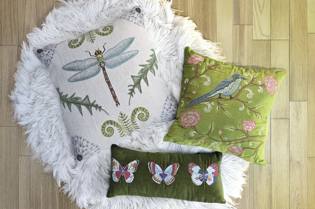 Decorative pillows with nature-themed designs on a wooden floor and shag rug.