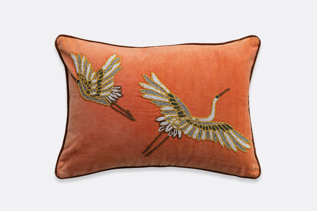 A beaded embroidered pillow featuring two flying cranes.