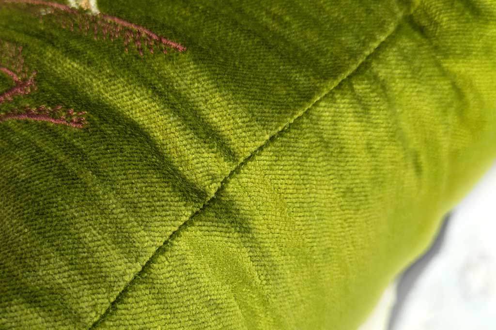Close-up of green velvety fabric with visible stitching