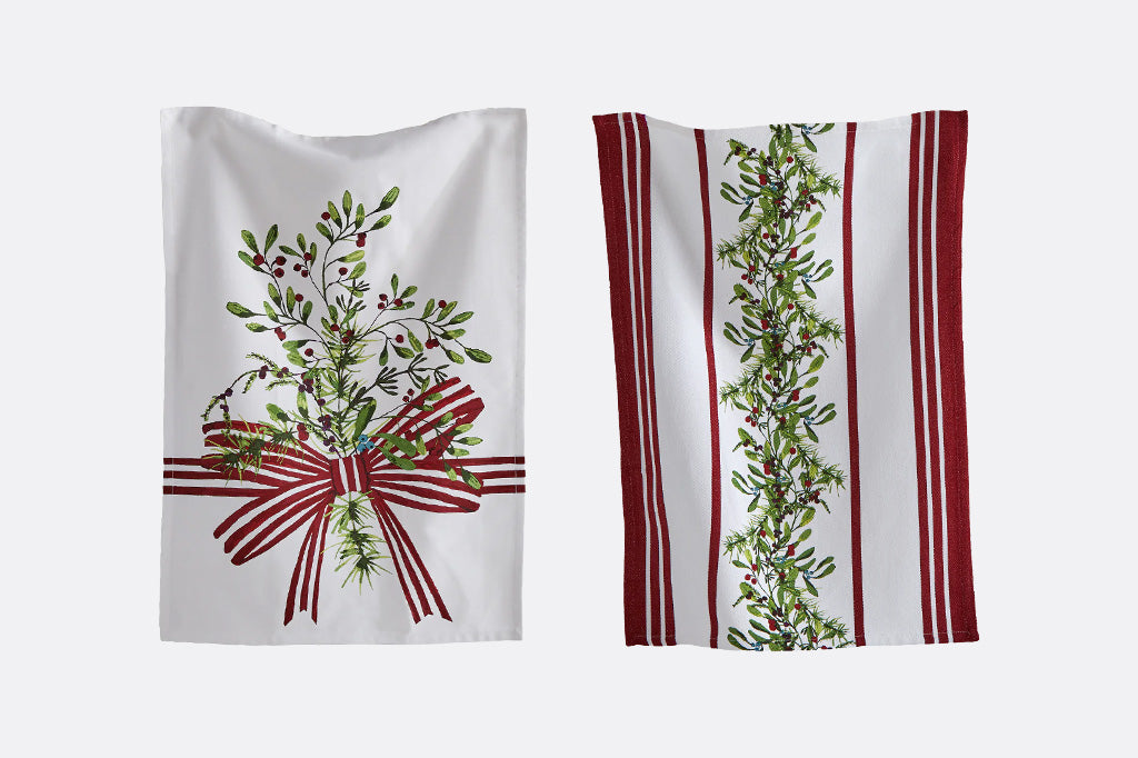 Two white kitchen towels with holiday designs, one featuring a green mistletoe and red ribbon motif, and the other featuring red and white vertical stripes with a green mistletoe garland down the center.